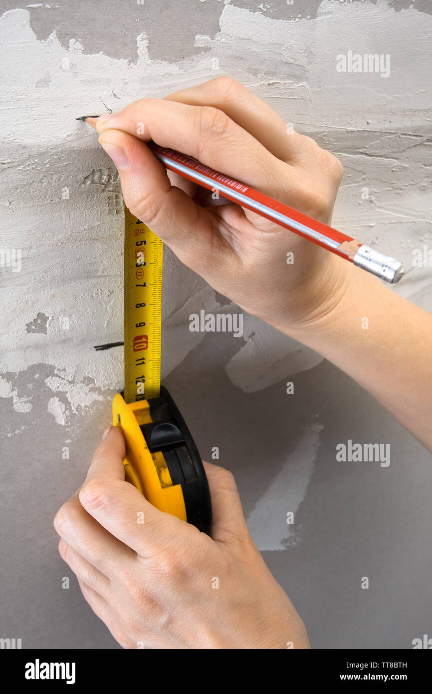 Hände messen Wand mit Maßband und Markierung an der Wand mit Bleistift  Stockfotografie - Alamy