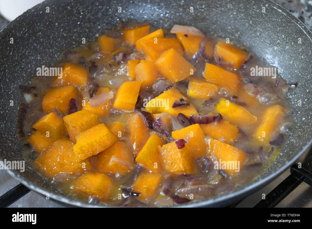 Die gewürfelten Kürbis geschmort in der Pfanne mit Zwiebeln Stockfoto