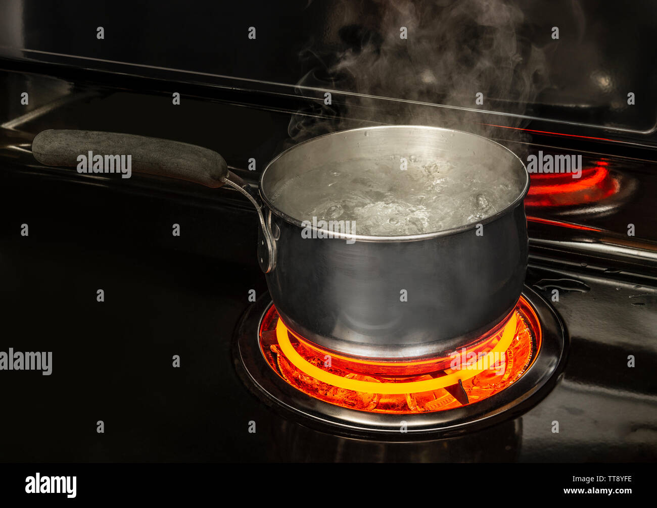 Horizontale geschossen von einem kochenden Topf Wasser auf eine Herdplatte mit einem rot glühenden Element mit kopieren. Stockfoto