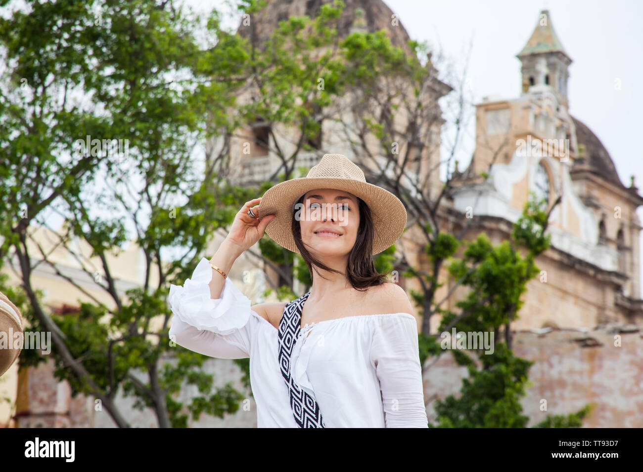 Schöne junge Frau, die versucht, auf die Hüte, die man von einem Straßenhändler in Cartagena de Indias zu kaufen ummauerten Stadt Stockfoto
