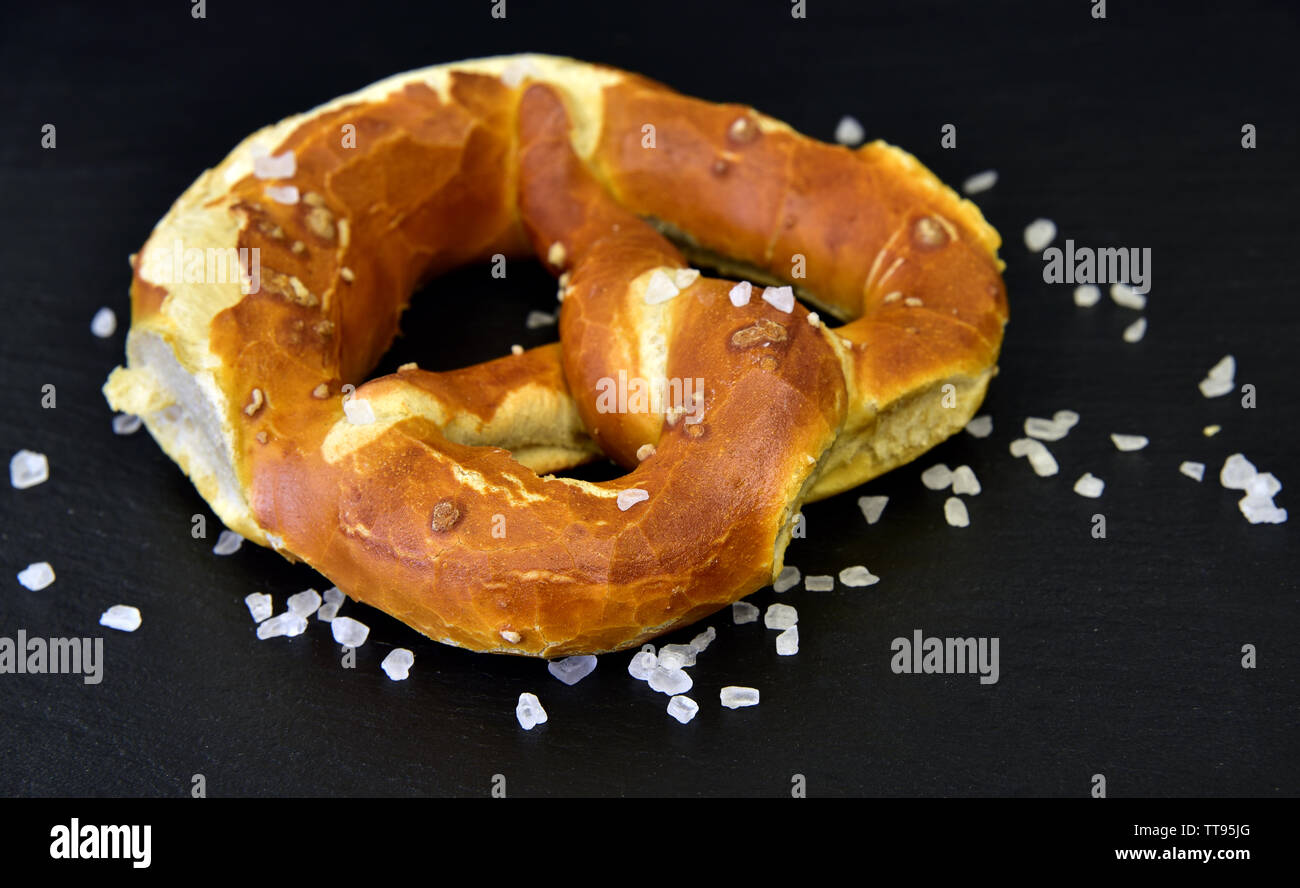 Eine leckere bayerische Brezel mit Salz vor einem dunklen Hintergrund Stockfoto