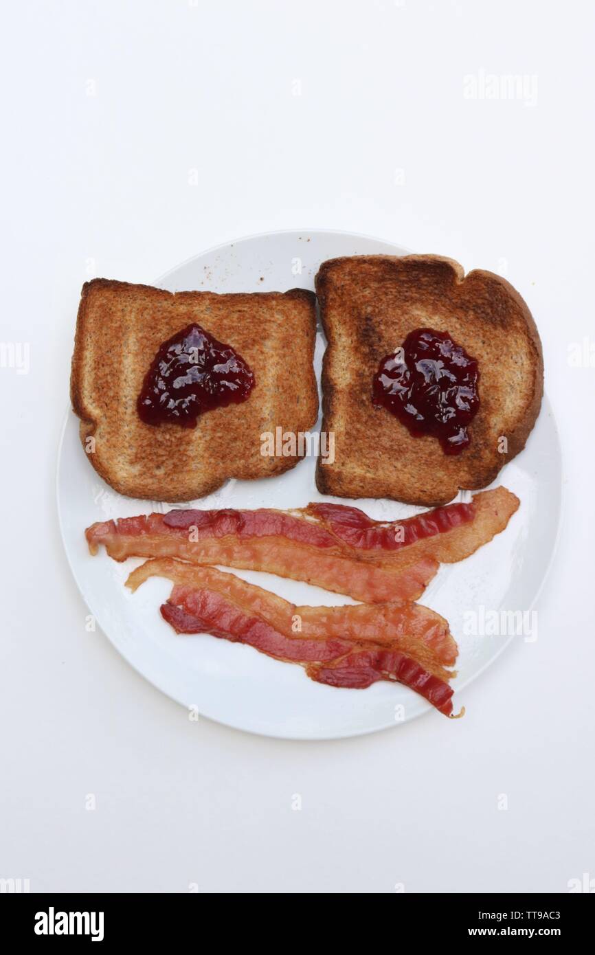Porträt einer Happy Meal; Jelly Toast und Speck angeordnet wie ein Smiley Stockfoto