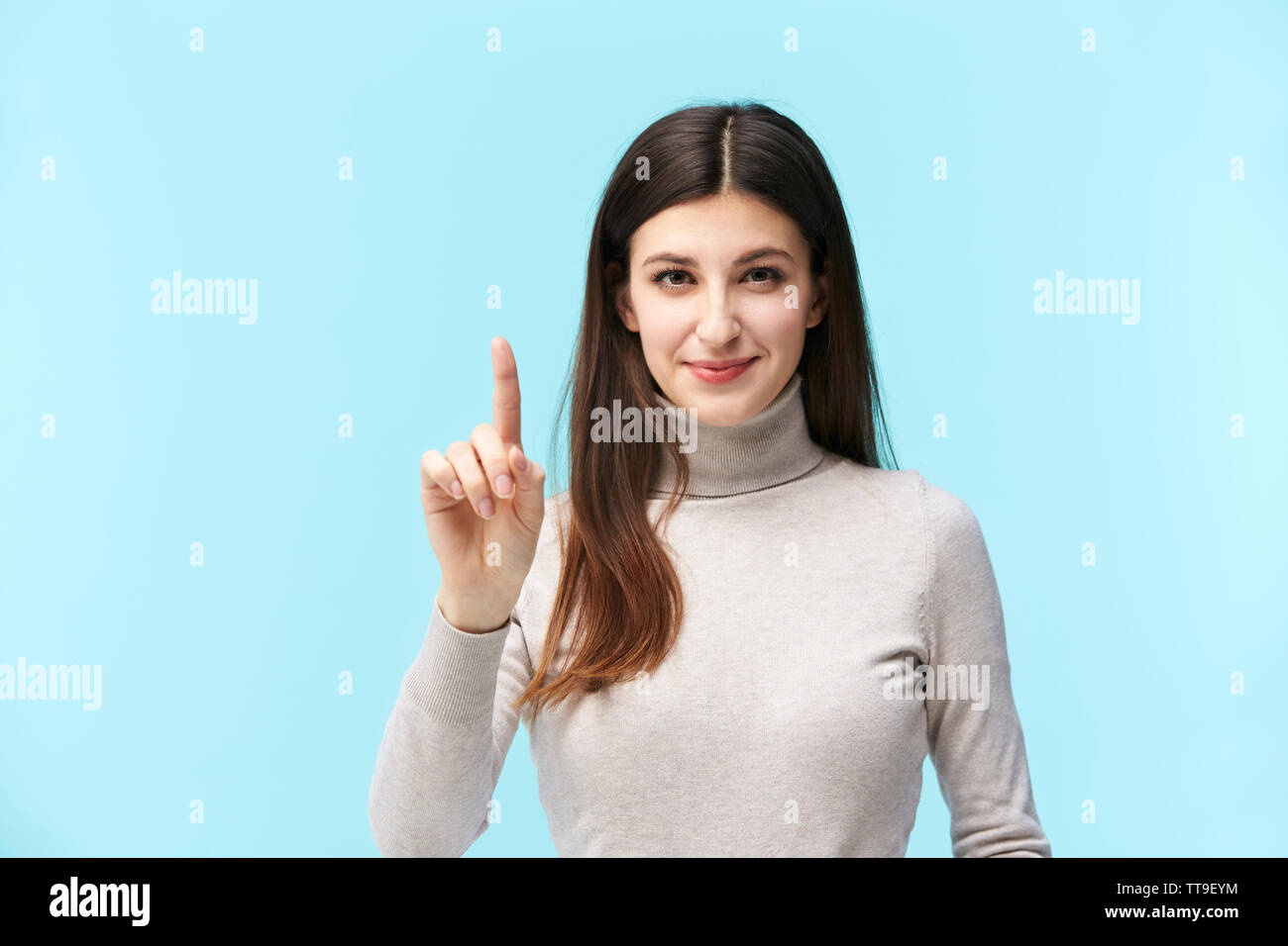 Schönen jungen kaukasischen Frau Drücken einer virtuellen Button, in die Kamera lächeln suchen, auf blauem Hintergrund isoliert Stockfoto