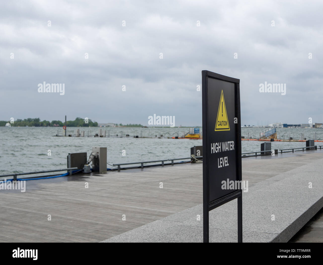 Toronto, Kanada. 15 Juni, 2019. Anmelden Warnung vor hohen Wasserstand auf Toronto Harbour Front, während Wasser spritzt zu Peer. Stockfoto