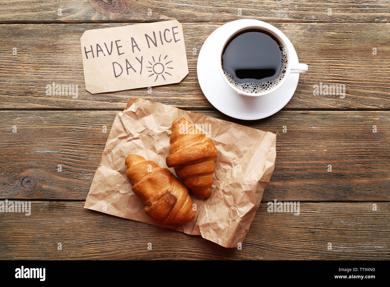 Tasse Kaffee mit frischen Croissant und einen schönen Tag Massage auf Holztisch, Ansicht von oben Stockfoto