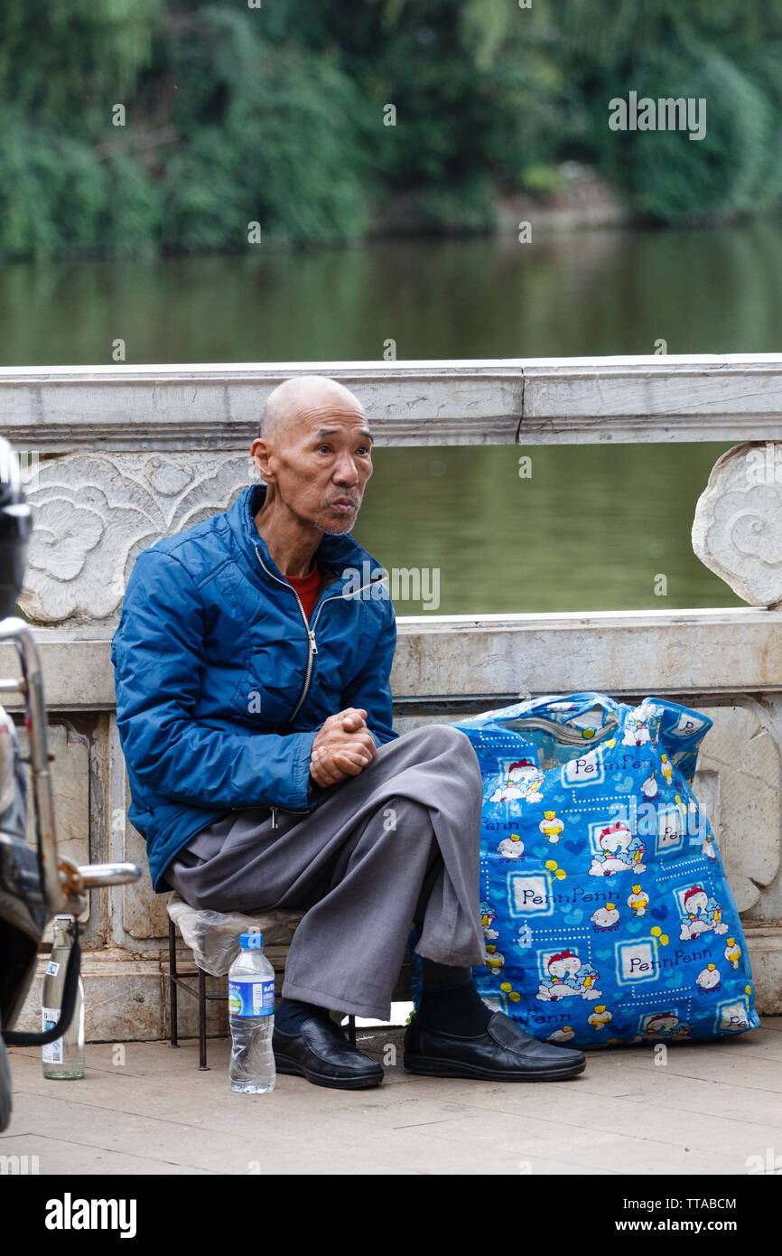 Edler Mann in einem Park in Kunming sitzen Stockfoto