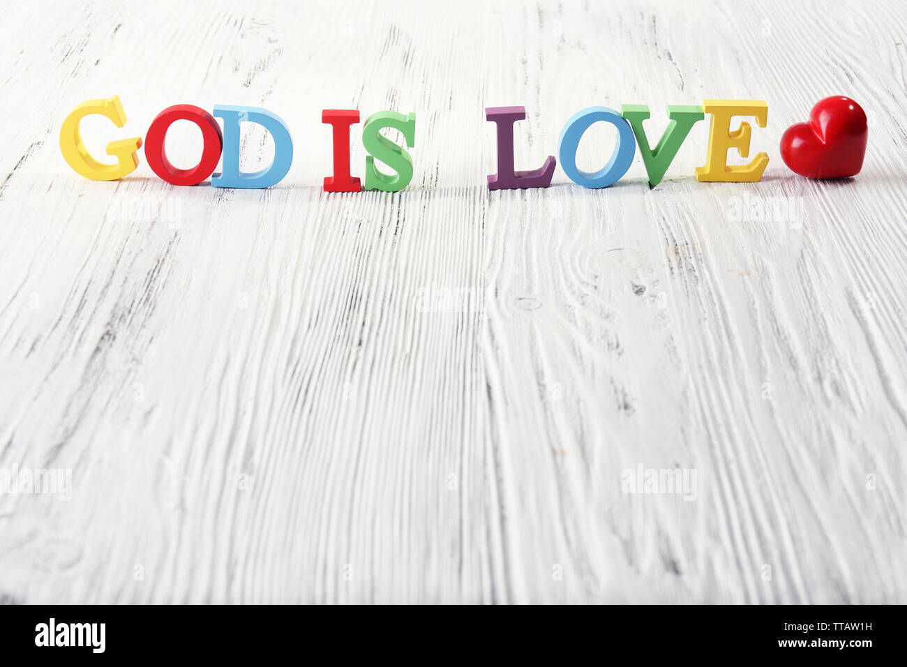Gott ist die Liebe mit bunten Kunststoff Holz Buchstaben auf weißem Hintergrund dargestellt Stockfoto