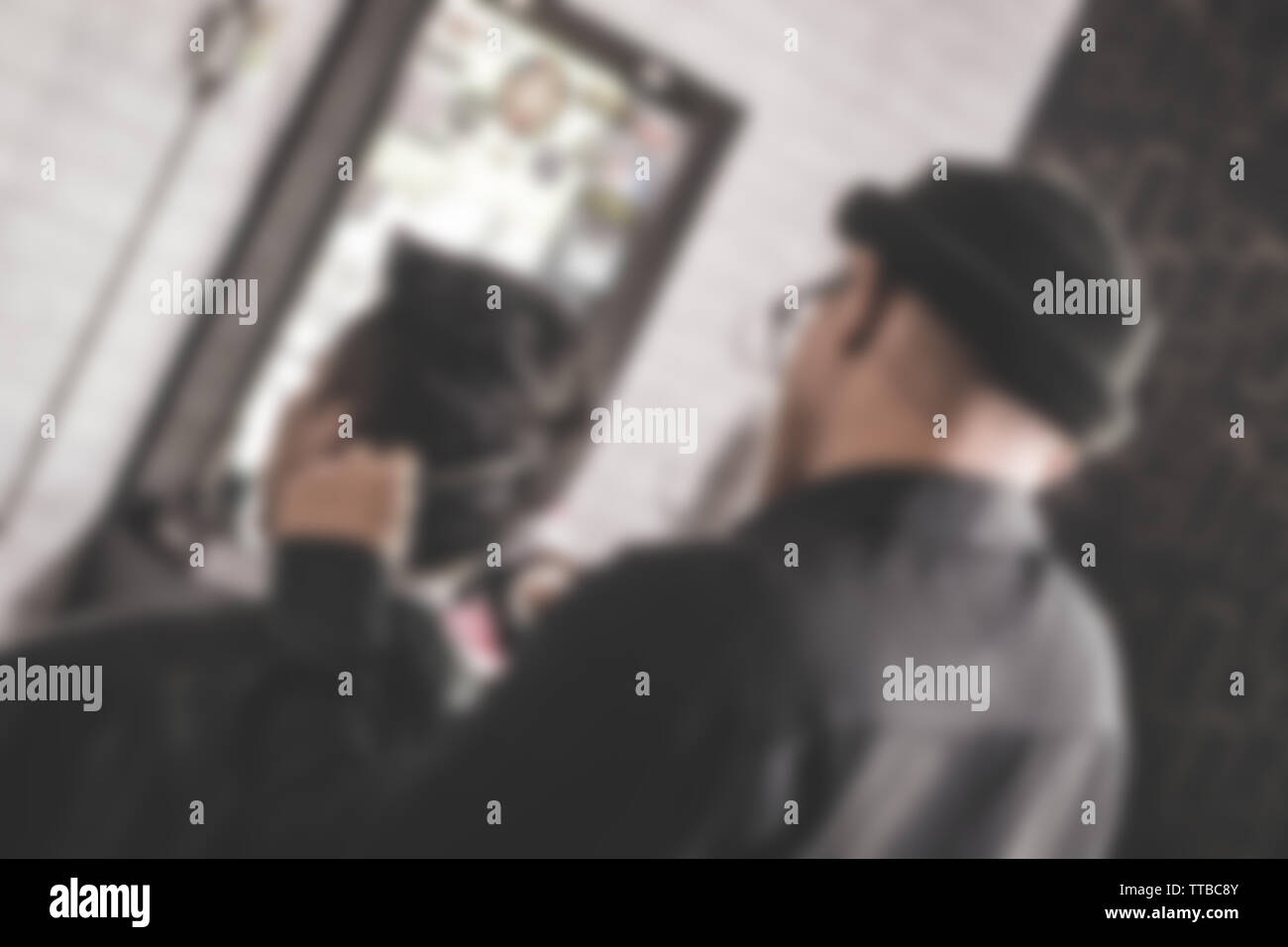 Blurry Rückansicht des Friseur- Mann mit schwarzen T-Shirt schnitt seine männlichen Kunden mit Schere und Kamm in Barbershop Stockfoto