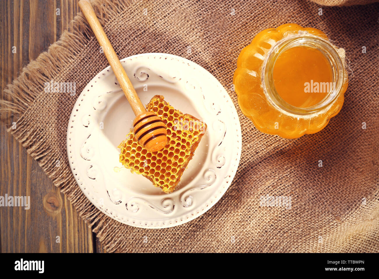 Topf mit Honig und Honigseim mit Pendelarm auf hölzernen Hintergrund Stockfoto