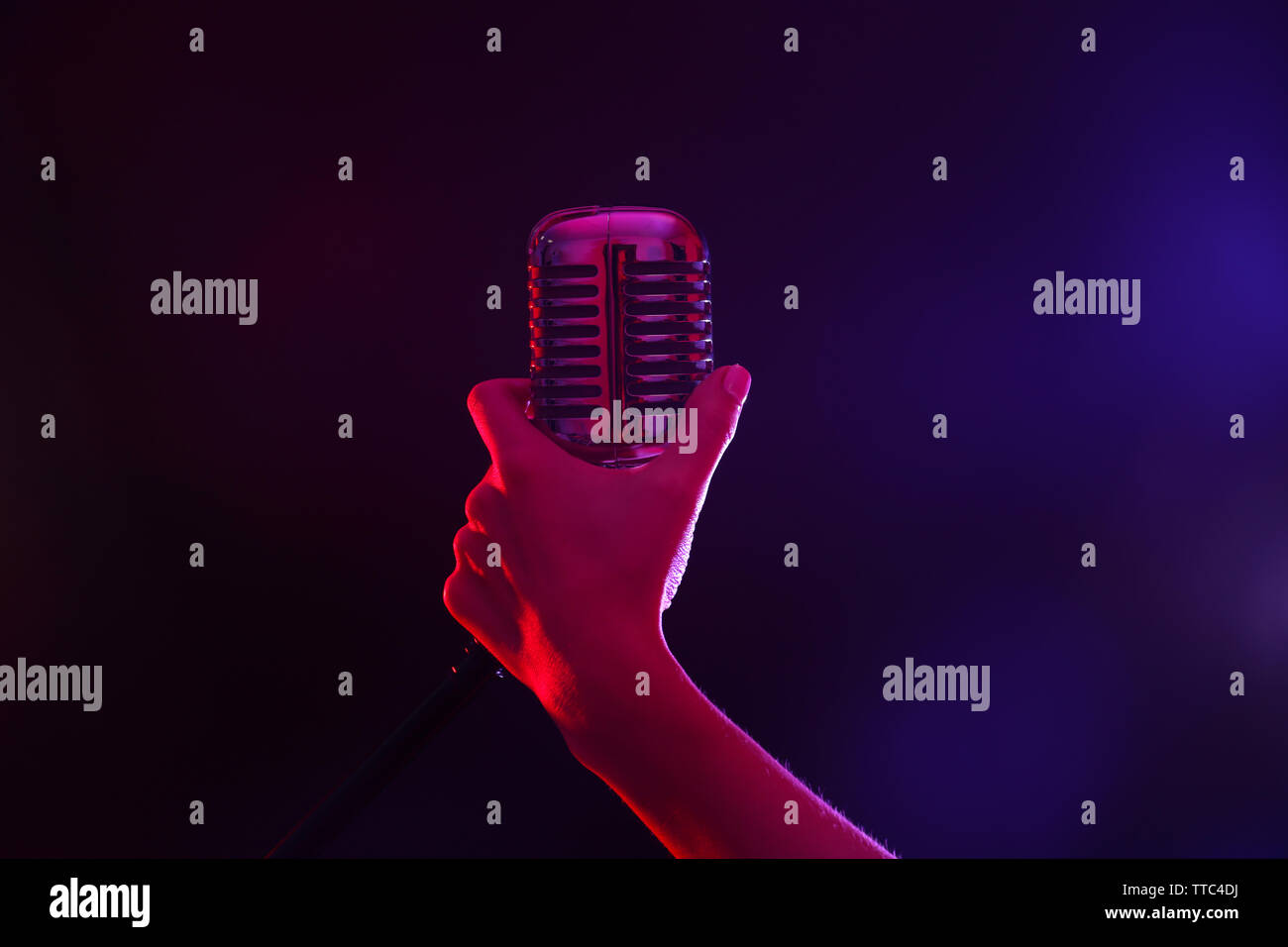 Weibliche hand mit einem retro Mikrofon gegen farbigen Hintergrund Stockfoto