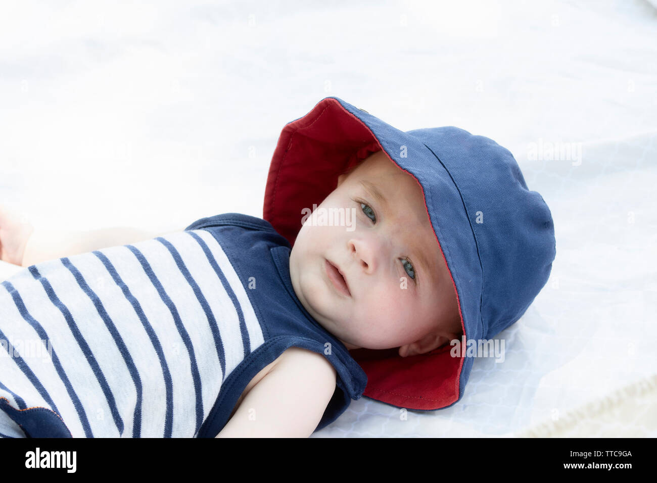 Blue-eyed Baby Junge lag auf dem Rücken auf Decke mit Hut für Sonnenschutz Stockfoto