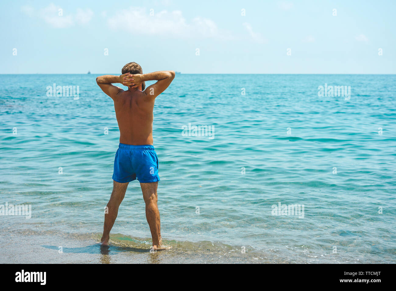 Bereit für die Berufung. Ein stattlicher Mann in Badehose auf exotischen karibischen Strand und mit Blick auf das Meer Stockfoto