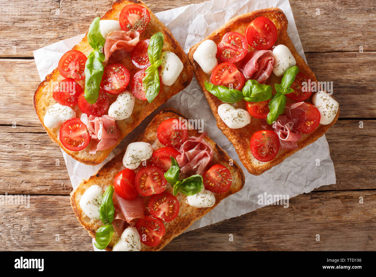Italienische Sandwiches mit Mozzarella, Tomaten, Schinken und Basilikum Nahaufnahme auf dem Tisch. Horizontal oben Ansicht von oben Stockfoto