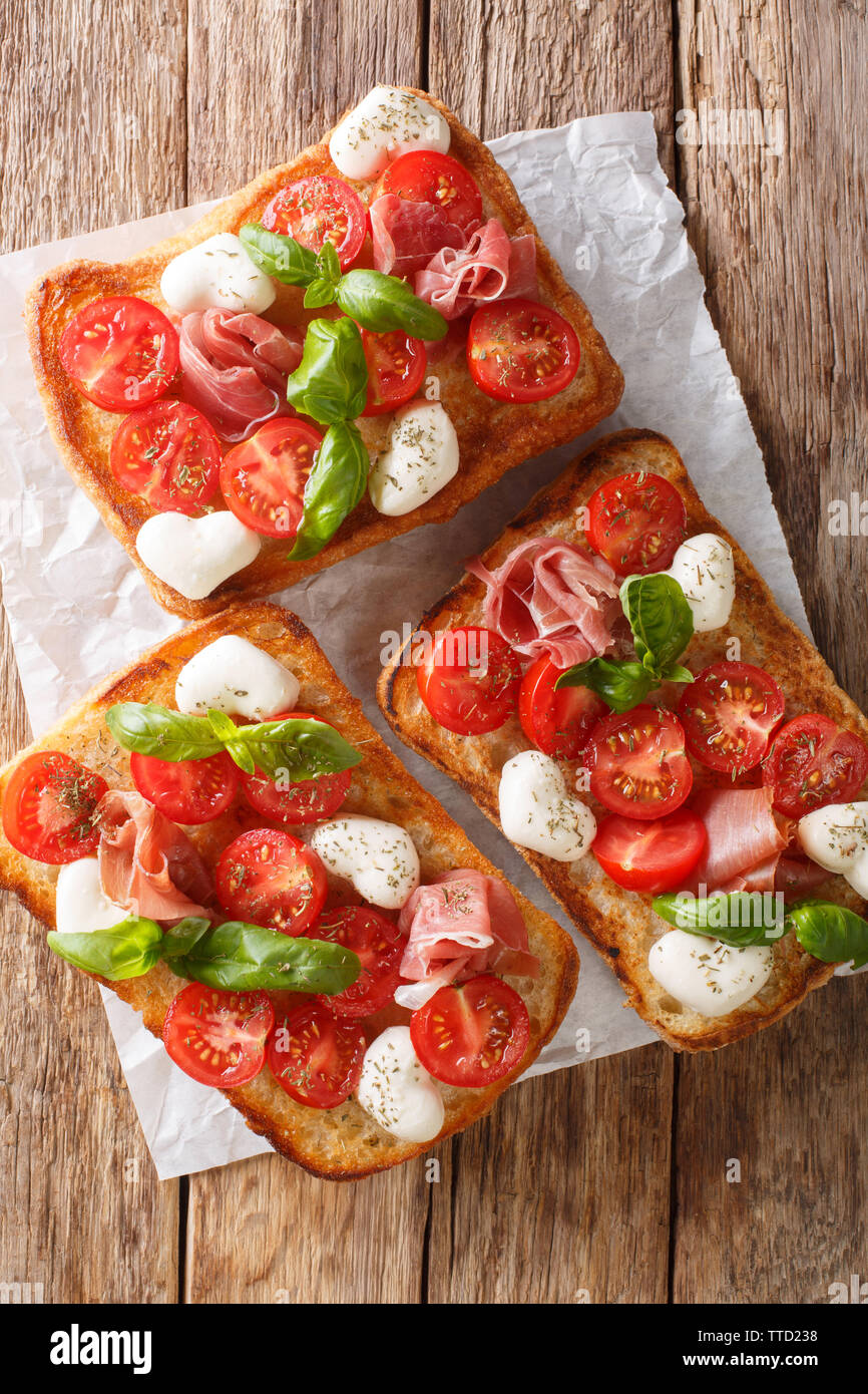 Italienische Sandwiches mit Mozzarella, Tomaten, Schinken und Basilikum Nahaufnahme auf dem Tisch. Vertikal oben Ansicht von oben Stockfoto