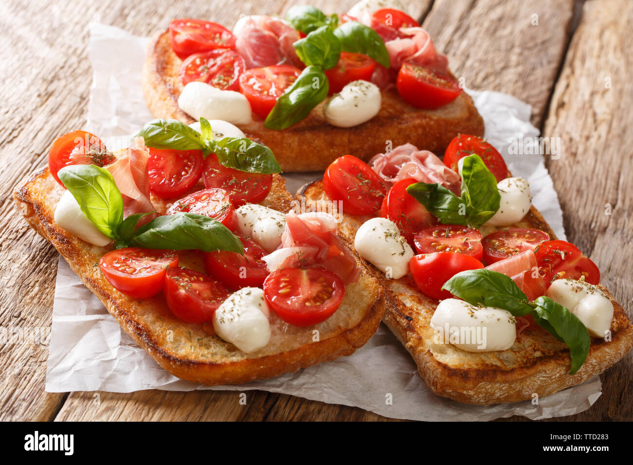 Italienische Sandwiches mit Mozzarella, Tomaten, Schinken und Basilikum Nahaufnahme auf dem Tisch. Horizontale Stockfoto