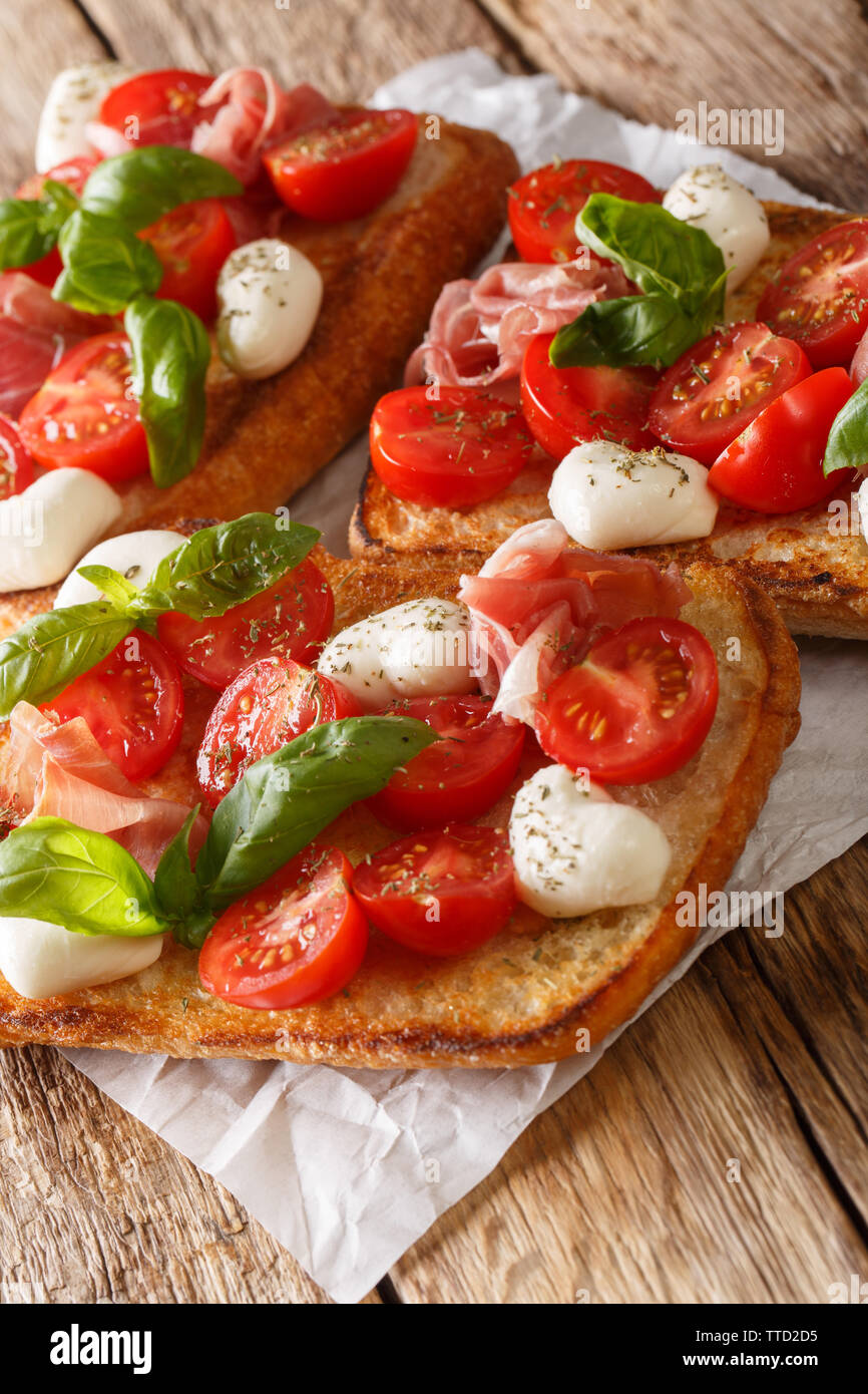 Hausgemachte Toast mit Mozzarella, Tomaten, Schinken und Basilikum close-up auf dem Tisch. Vertikale Stockfoto