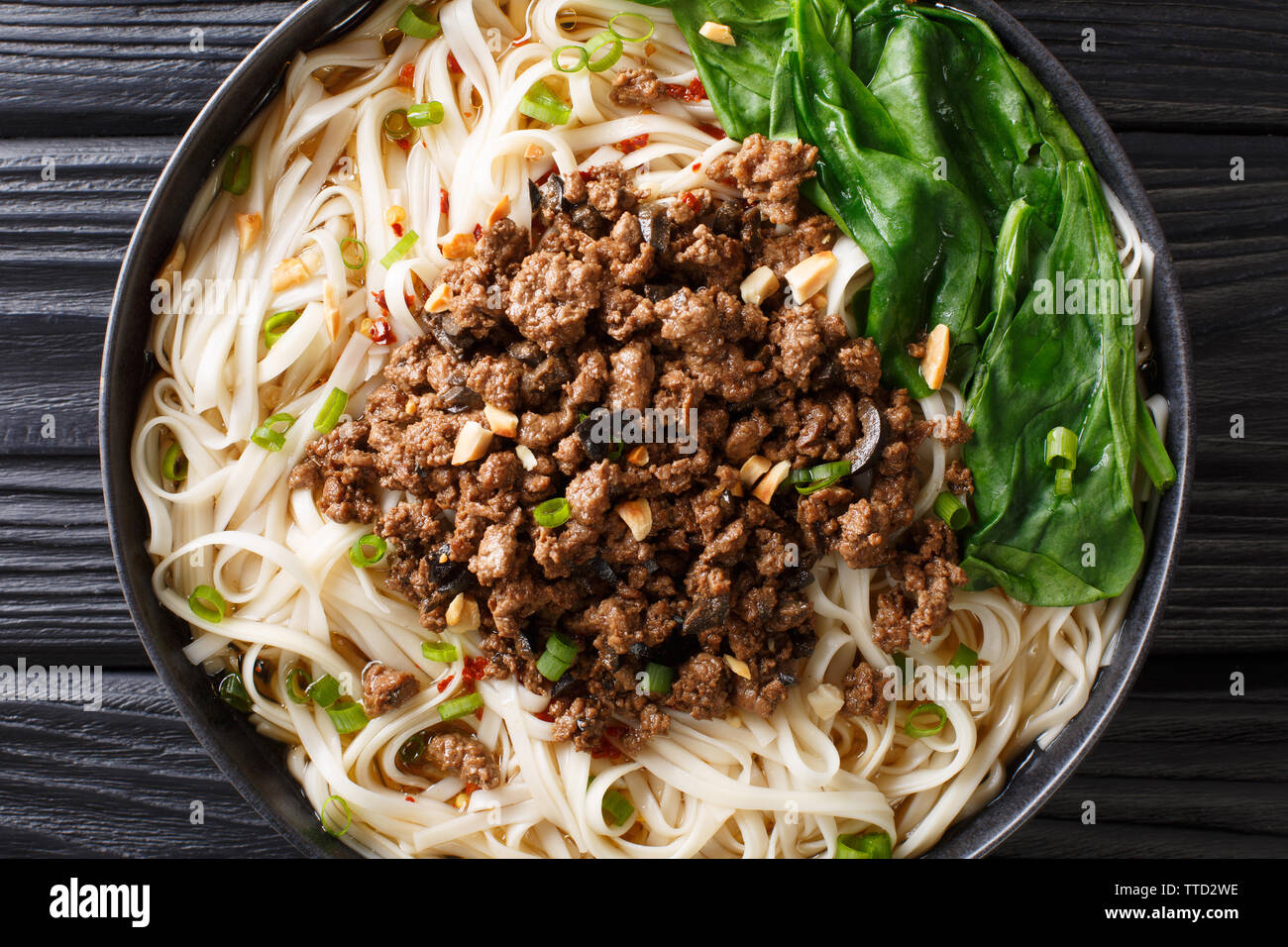 Dan Dan Nudeln - herzhaft und würzig Sichuan Nudeln serviert mit Hackfleisch Nahaufnahme auf dem Teller auf dem Tisch. horizontal oben Ansicht von oben Stockfoto