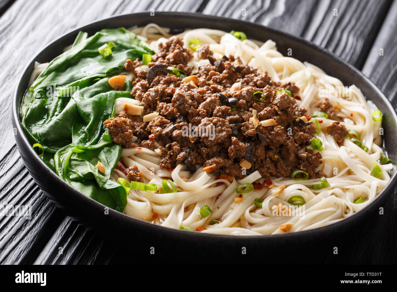 Traditionelle Chinesische Sichuan Dan Dan Nudeln mit Hackfleisch und Grüns in einen Teller auf dem Tisch. Horizontale Stockfoto