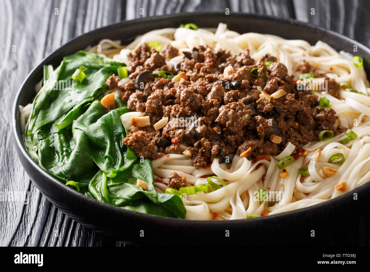 Rezept für dan dan Nudeln mit Hackfleisch und Grünen closeup in einem Teller auf dem Tisch. Horizontale Stockfoto