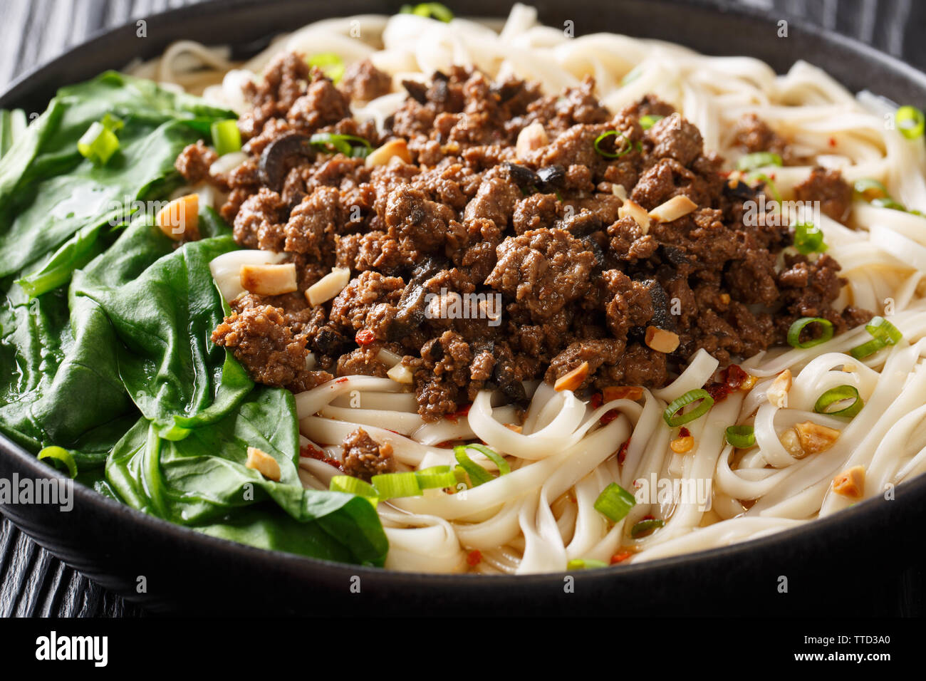 Sichuan Dan Dan Nudeln mit Hackfleisch und Grünen closeup in einem Teller auf dem Tisch. Horizontale Stockfoto