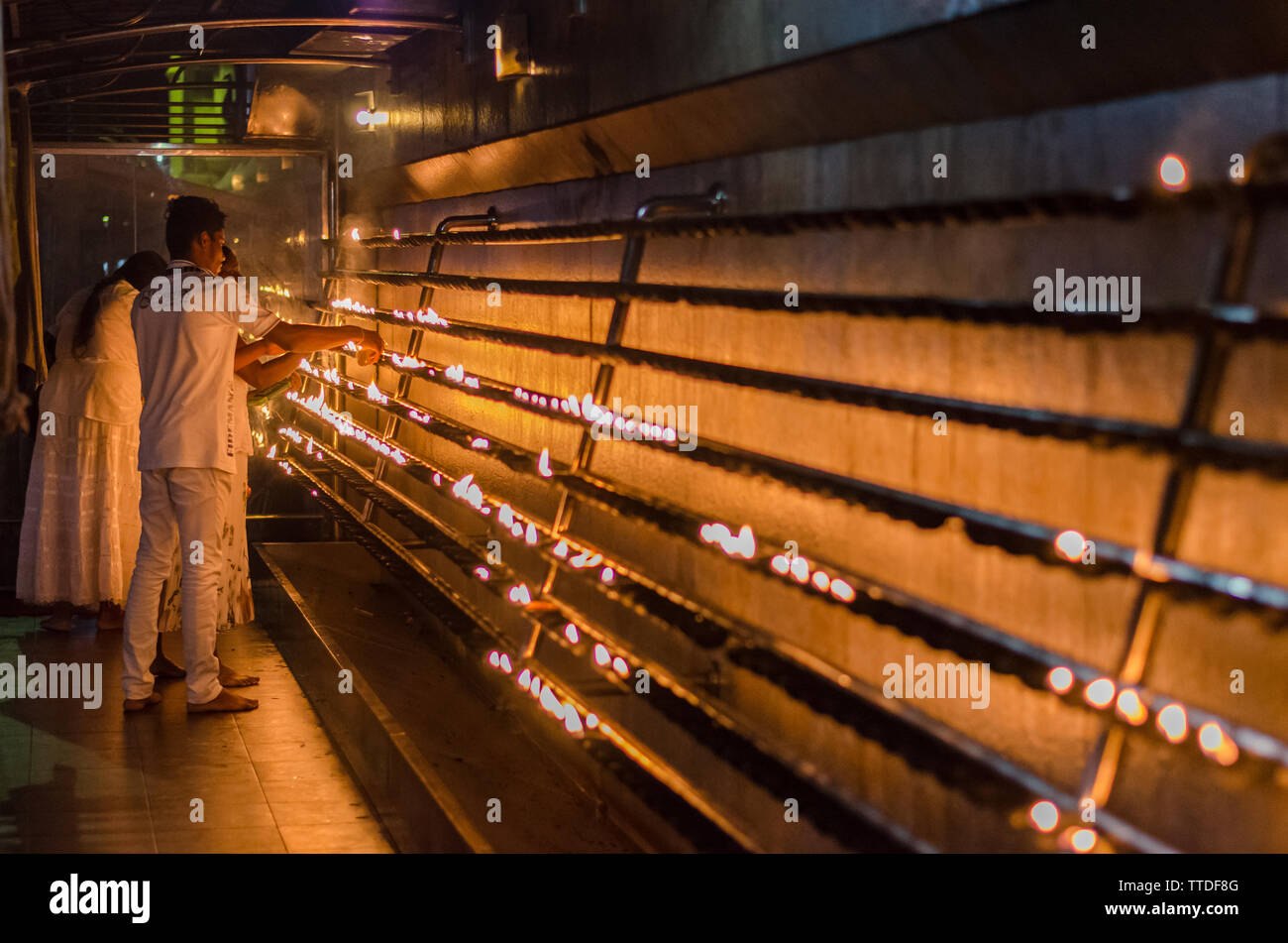 Eine Frau leuchtet eine Kerze in einem Tempel in Kataragama, Sri Lanka Stockfoto