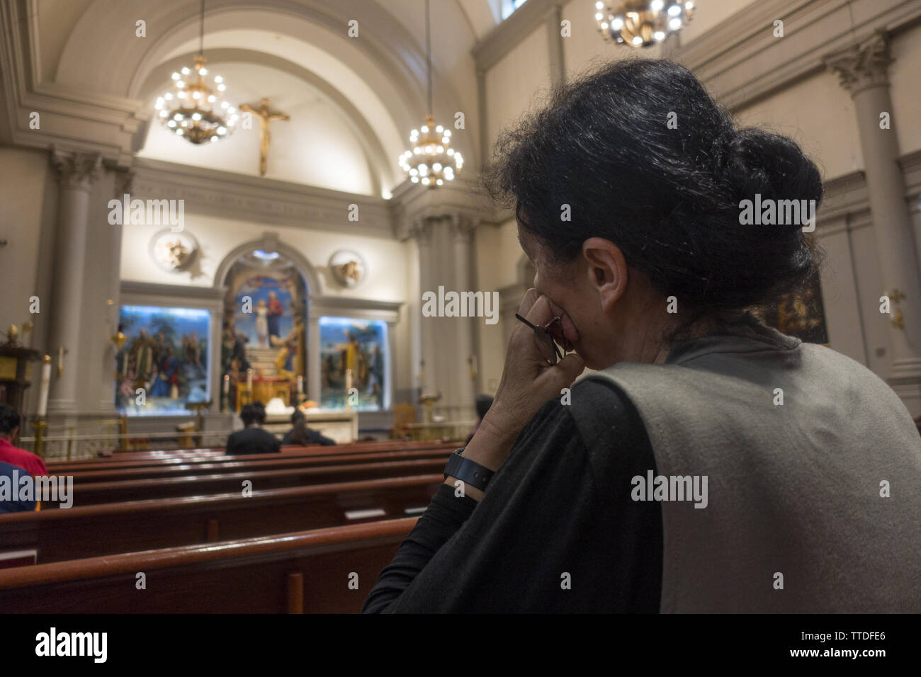 Frau tief in Gedanken an einer katholischen Kirche in Midtown Manhattan. Stockfoto