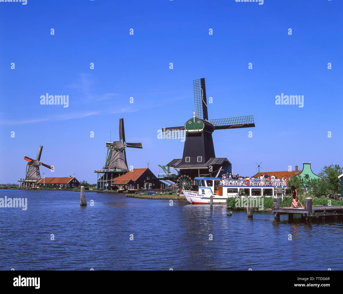 Touristische Ausflugsschiff gegen Windmühlen in Zaanse Schans, Zaandam, Noord-Holland, Königreich der Niederlande Stockfoto