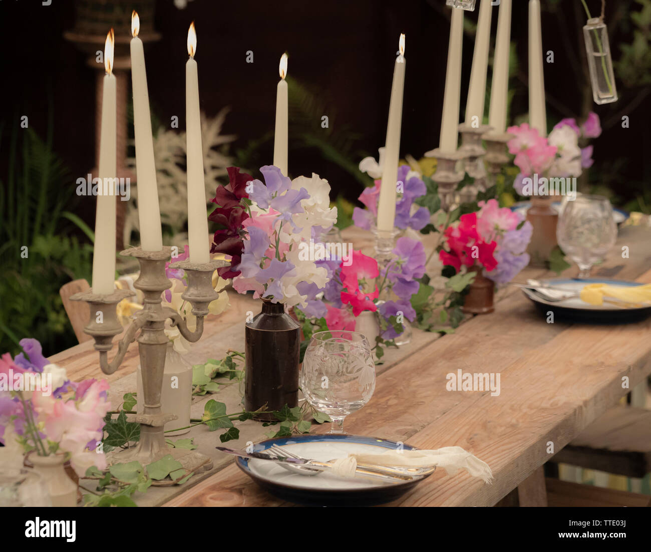 Garten Tisch mit Kerzen und Sweet pea Blumen Stockfoto