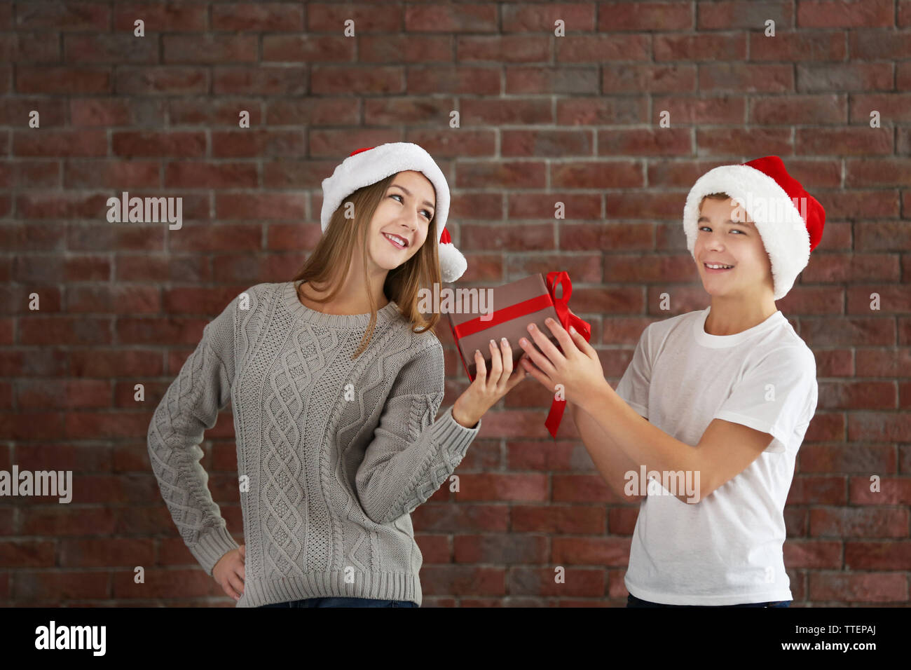 Glückliche Schwester und Bruder mit Geschenkbox auf Mauer Hintergrund Stockfoto