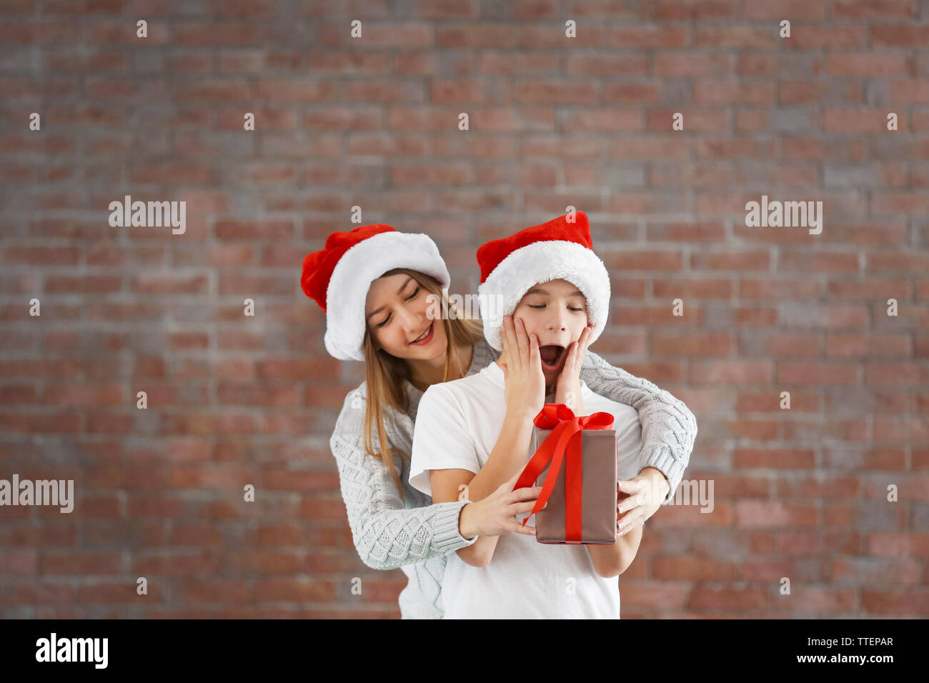 Glückliche Schwester und Bruder mit Geschenkbox auf Mauer Hintergrund Stockfoto