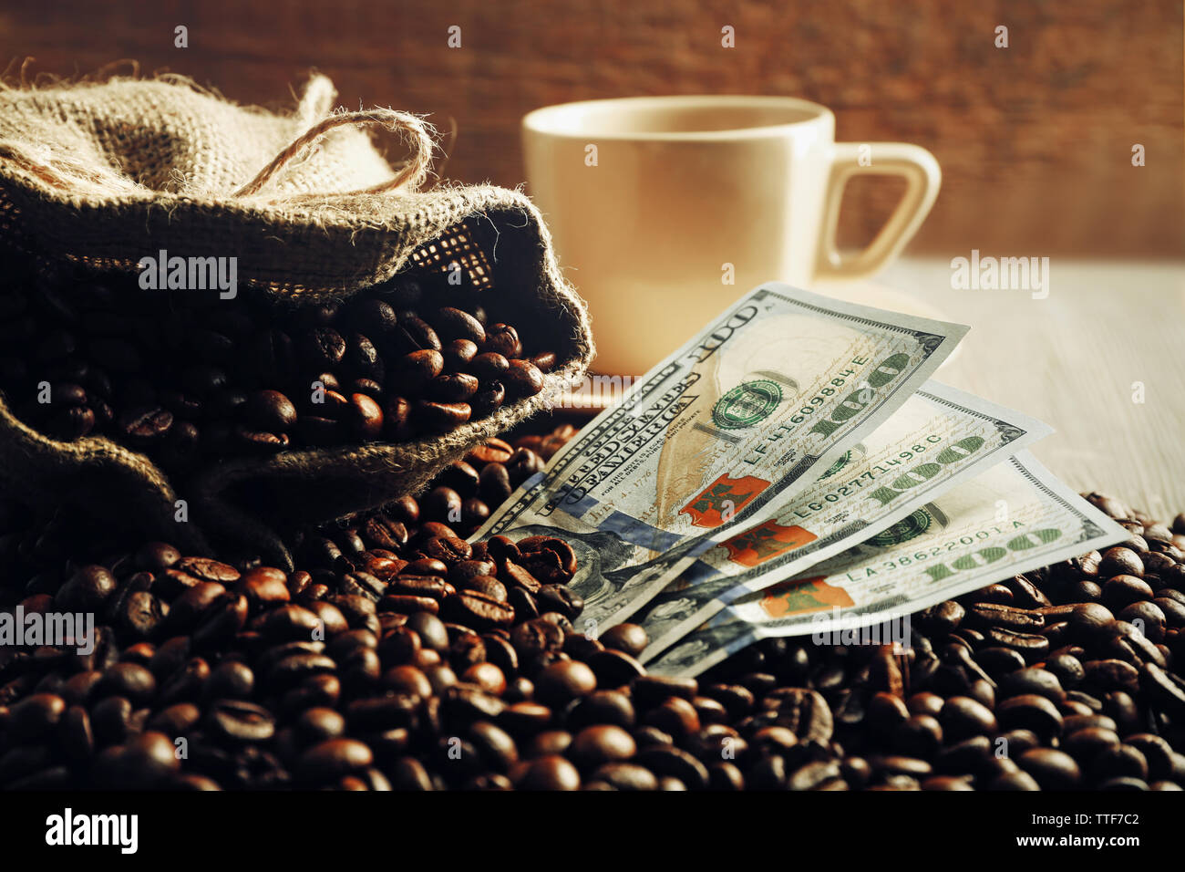 Kaffeebohnen, Tasse und US Dollar Banknoten auf hölzernen Hintergrund Stockfoto