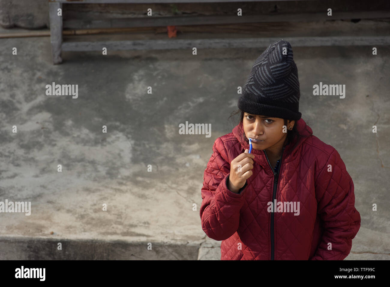 Ein Indisches Mädchen ist das putzen ihre Zähne in einem Winter morgen warme Kleidung tragen Stockfoto