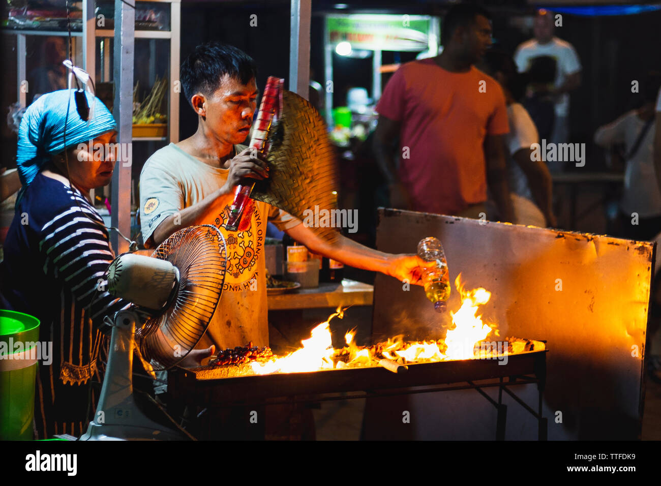 Mann und Frau Vorbereiten der Nahrung zu einem Nachtmarkt in Bali, Indonesien Stockfoto
