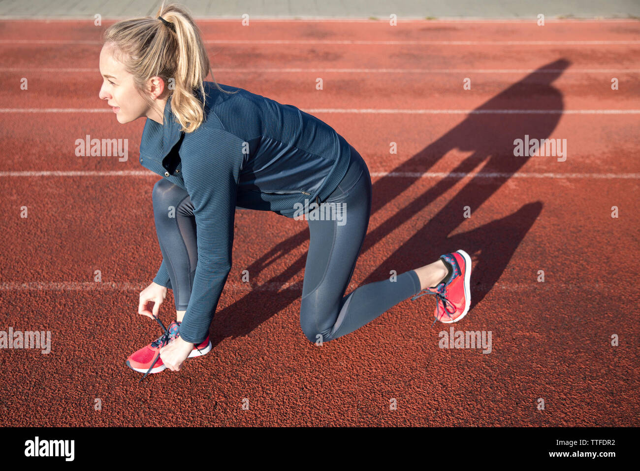 Seitenansicht der Sportlerin, die Schnürsenkel zu binden, am Sportplatz Stockfoto