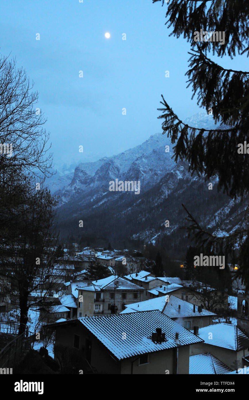 Schnee bedeckte Häuser am Berg gegen Himmel bei Dämmerung Stockfoto