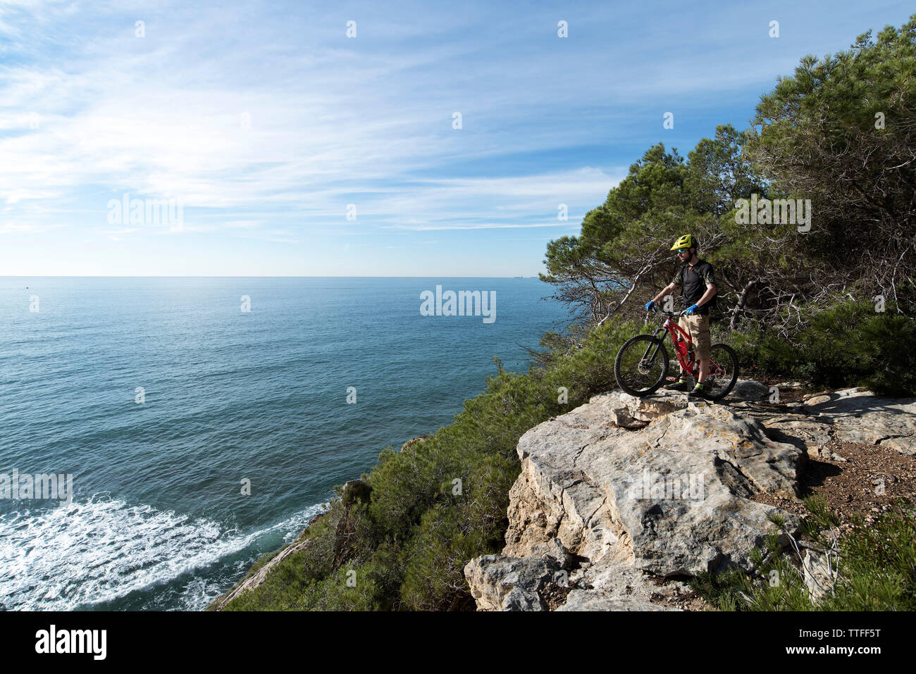 Mountainbiker stehen oben auf dem Felsen, Blick auf Meer. Stockfoto