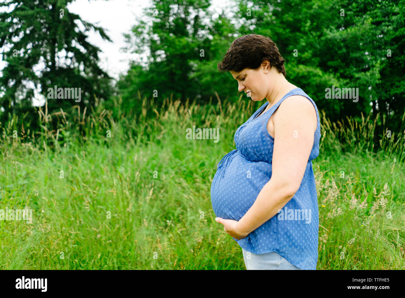 Seitliche Sicht auf eine schwangere Frau in ihrem Bauch nach unten schauen. Stockfoto