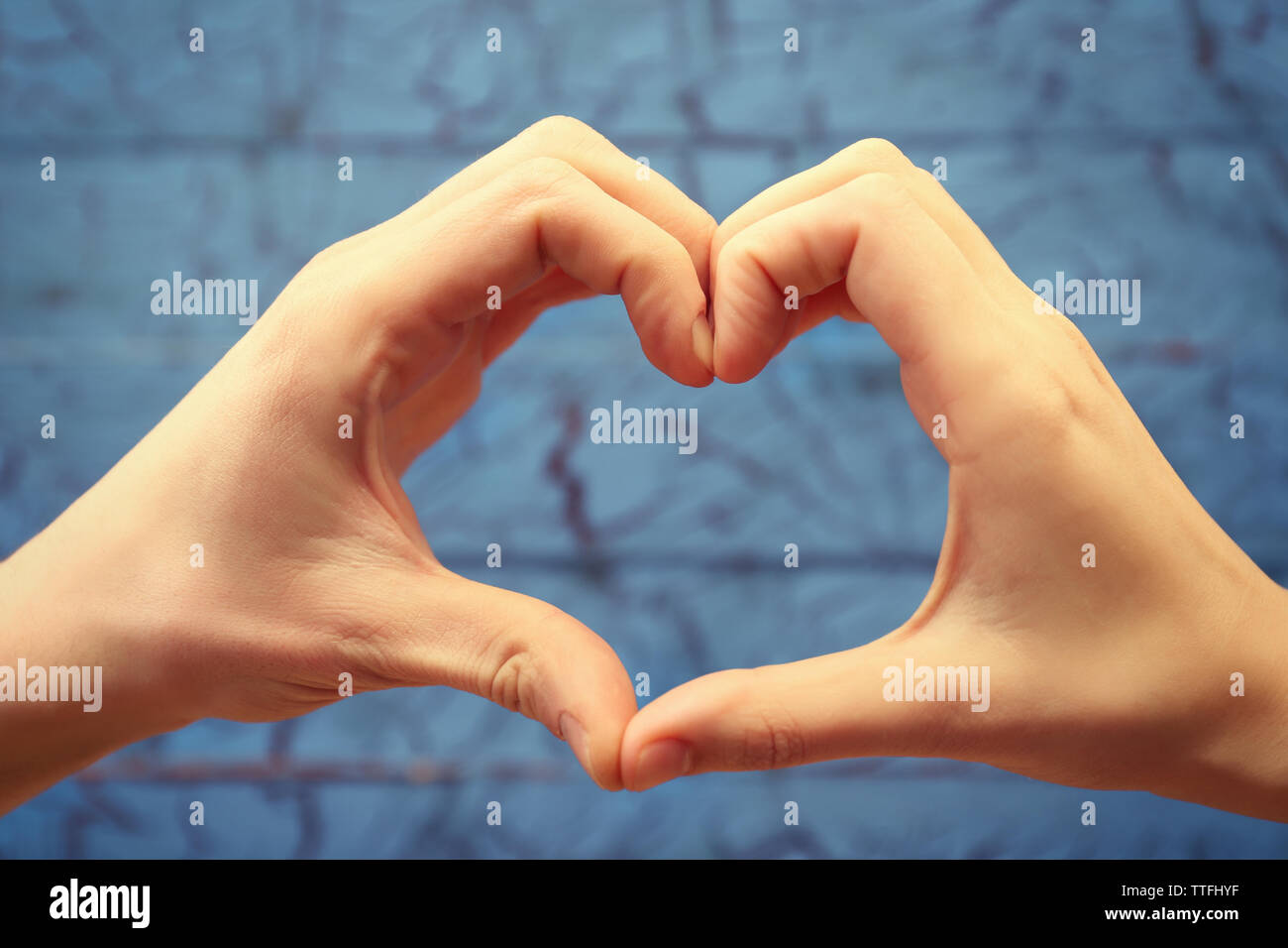 Männliche und weibliche Hände, Herzen, mit Fingern auf Blau Holz- Hintergrund Stockfoto