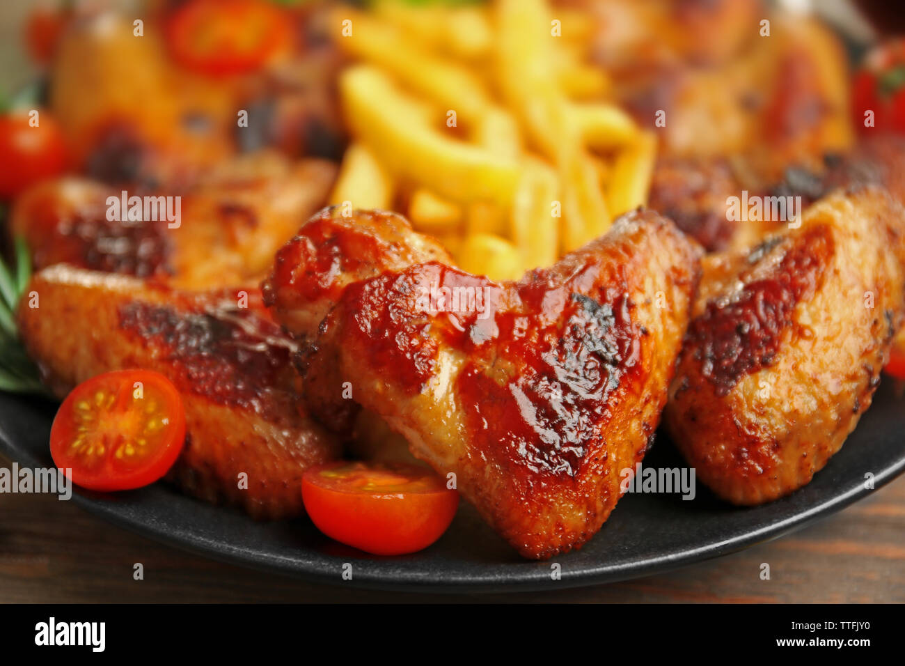 Gegrillte Chicken Wings mit Pommes frites, Garten - Personal und Tomaten auf Platte Stockfoto