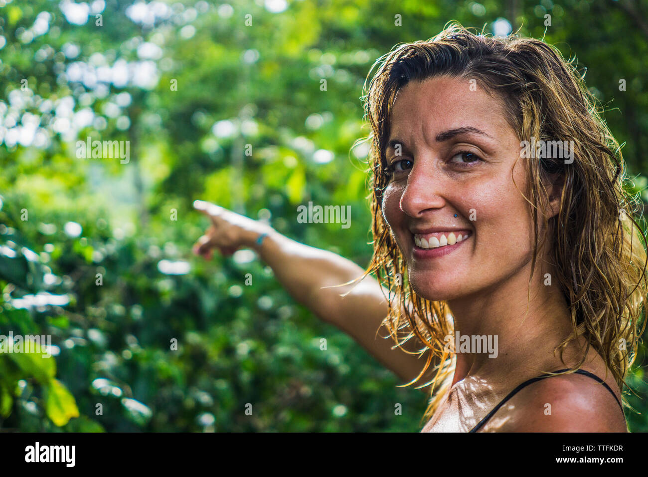 Portrait von glücklichen Mitte der erwachsenen Frau in Richtung Bäume im Wald zeigen Stockfoto