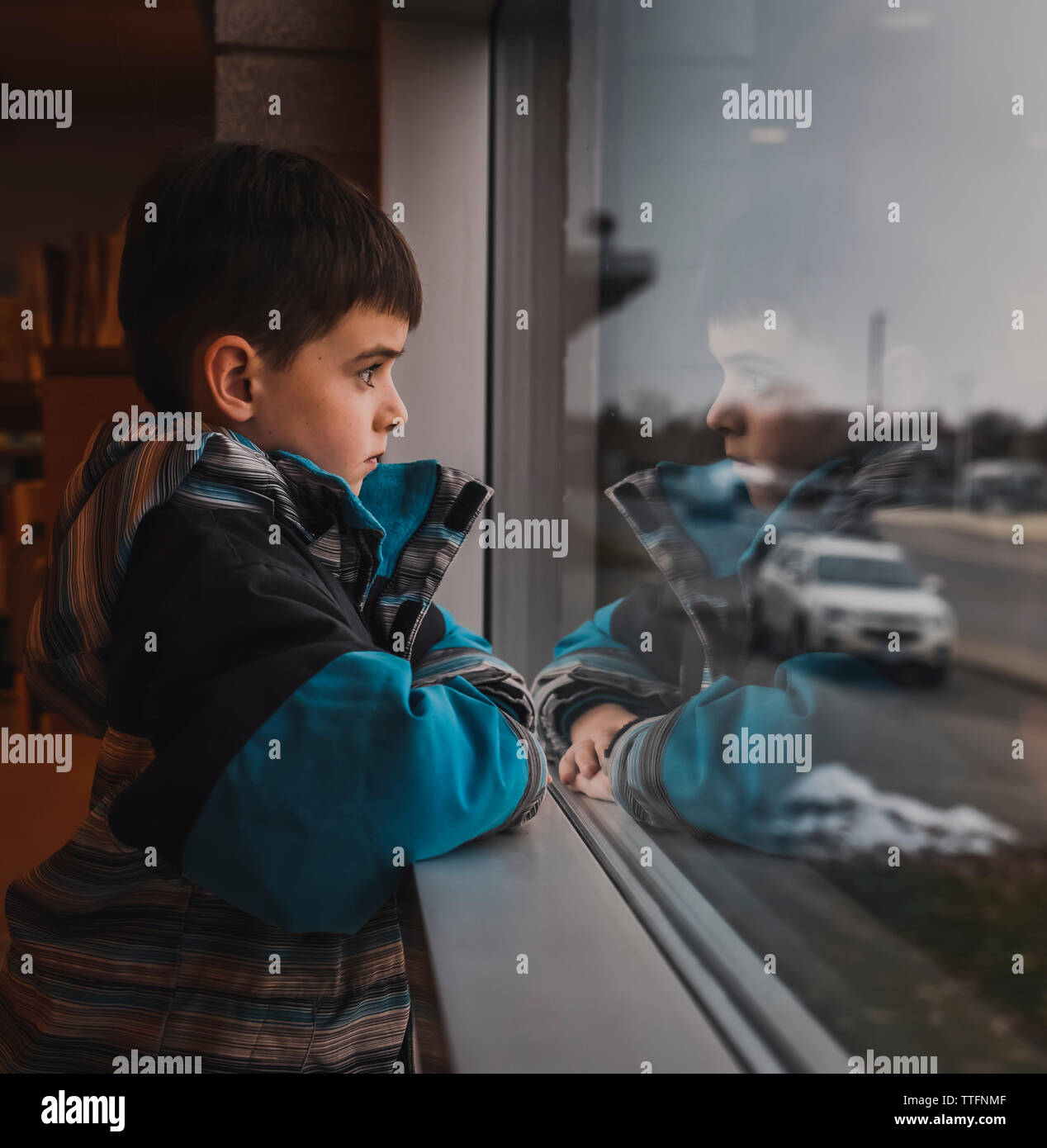 Junge tragen Winter Mantel aus Fenster an belebten Straße Stockfoto