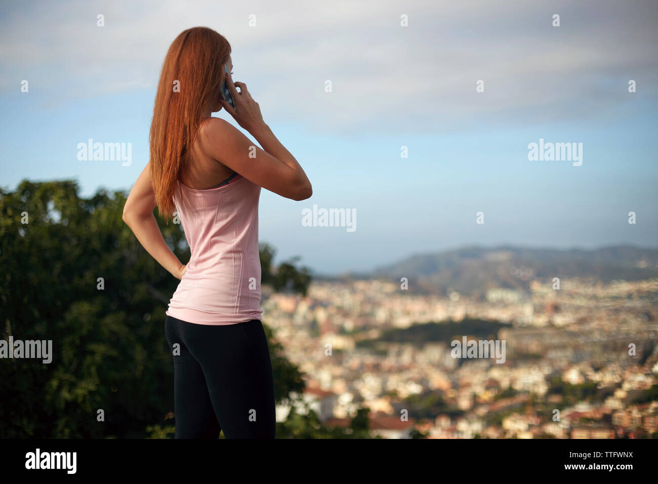 Frau sprechen über Smart Phone beim Stehen gegen Stadtbild und Sky Stockfoto