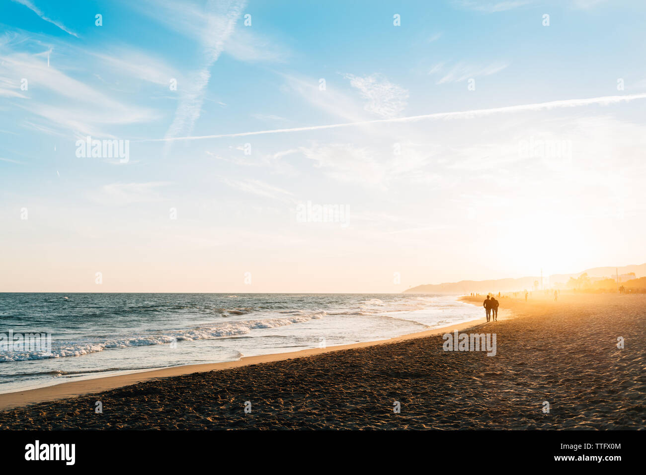 Paar Silhouetten zu Fuß am Strand entlang der Küste bei Sonnenuntergang Stockfoto