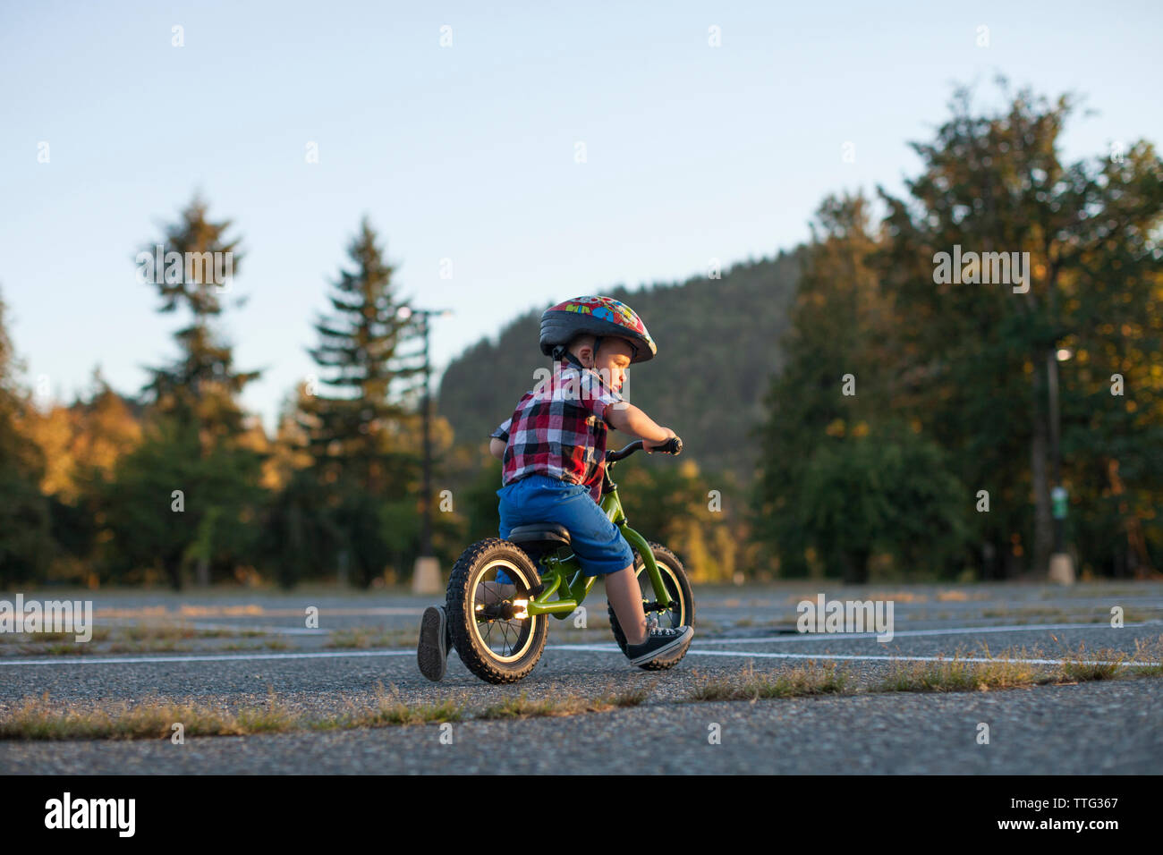 Volle Länge des Jungen tragen Fahrrad Helm beim Radfahren im Park Stockfoto