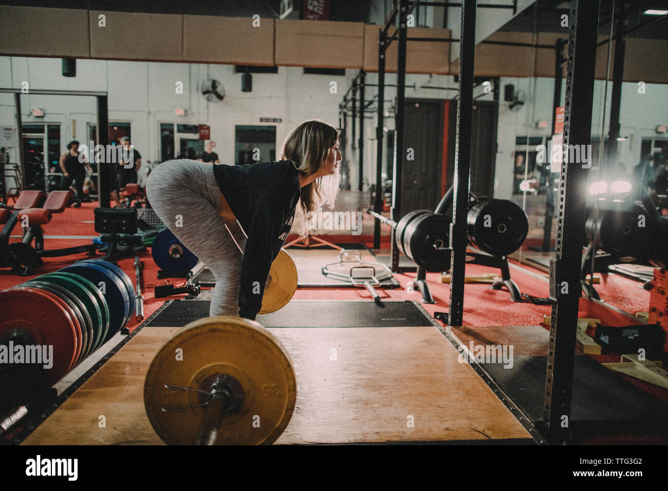 Seitenansicht des attraktiven Tausendjährigen gealterte Frau Ausbildung auf dem Squat Rack Stockfoto
