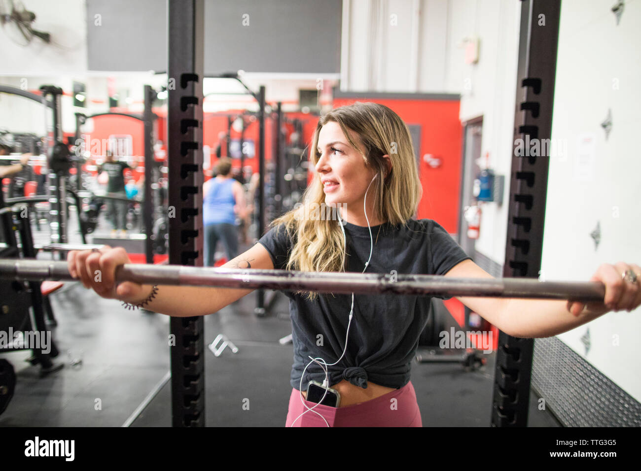 Nachdenkliche Frau lehnte sich auf Barbell in der Turnhalle Stockfoto