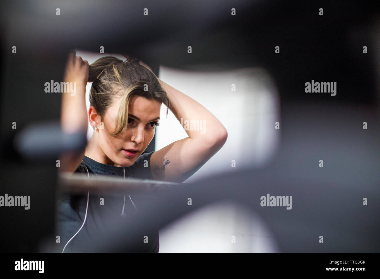 Attraktive Frau Riegel ihr Haar bei einem Workout im Fitnessraum. Stockfoto