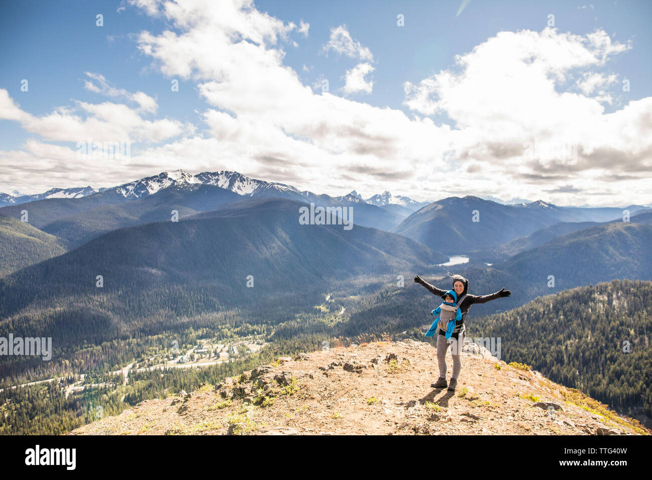 Aktive Mutter steht auf dem Gipfel der Cascade Lookout mit Baby Stockfoto