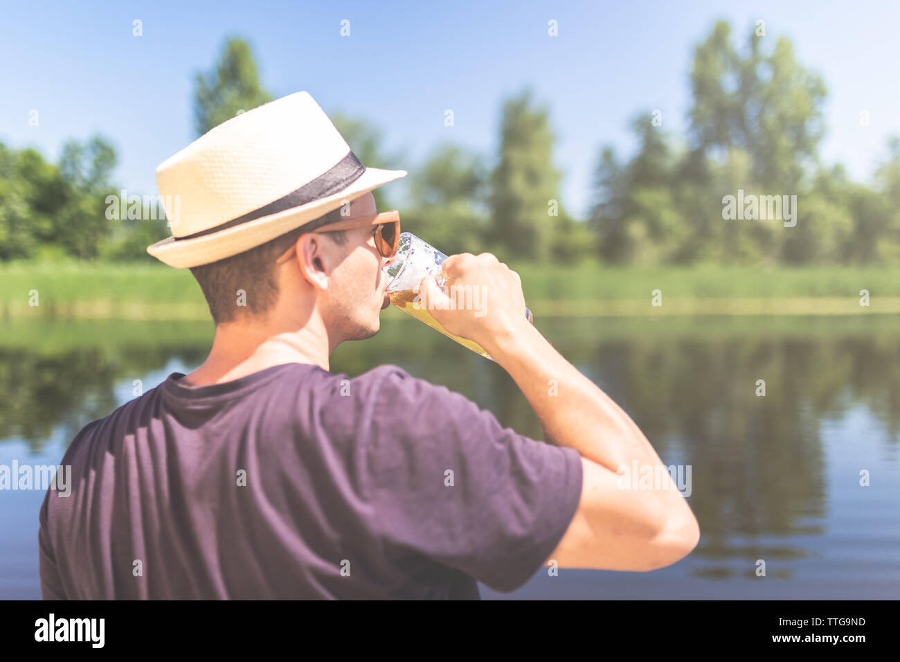 Ansicht der Rückseite des jungen Mann mit Strohhut und trinken Bier vor der wunderschönen Natur. Stockfoto