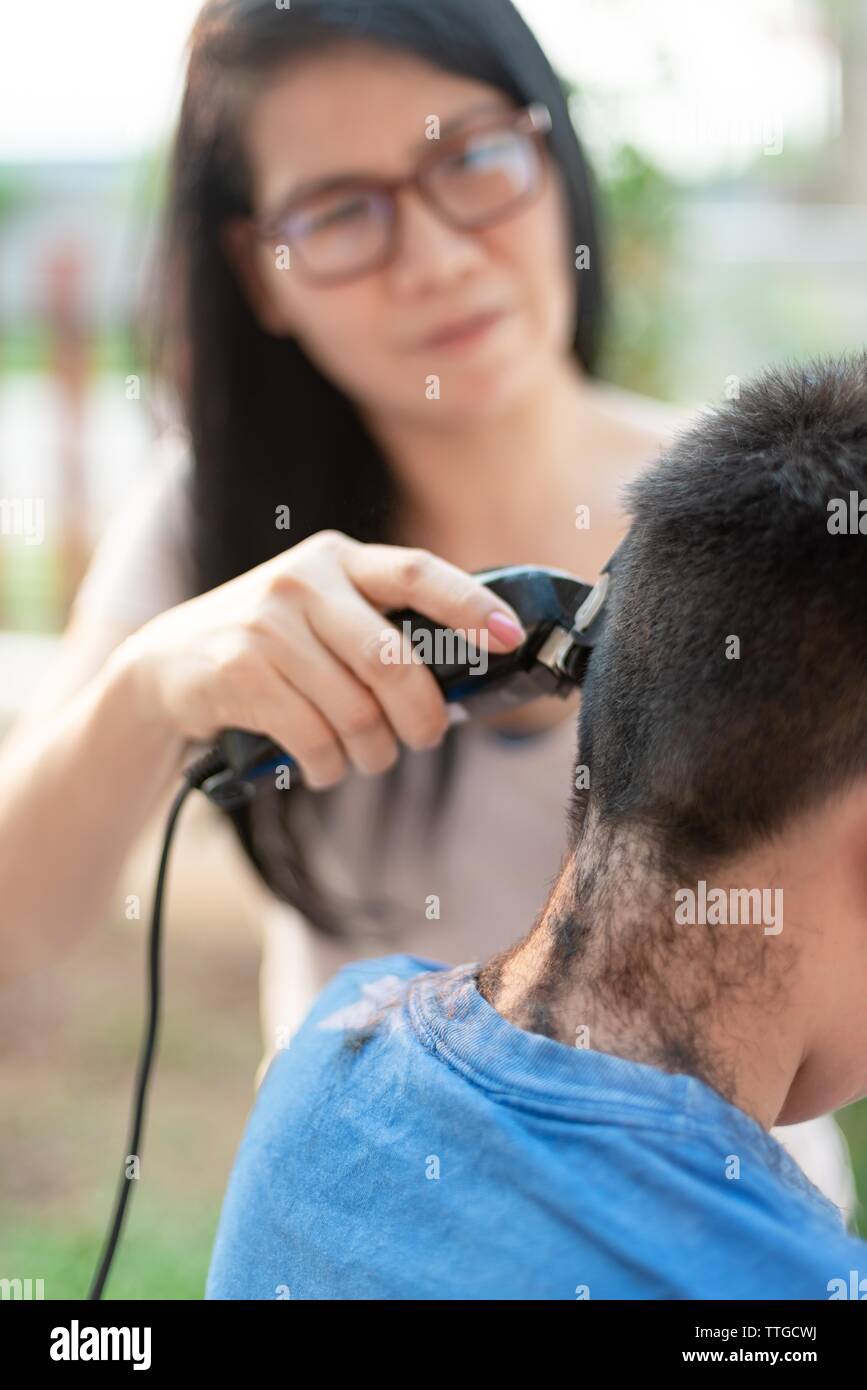 Mutter schneiden Haare für Sohn Stockfoto